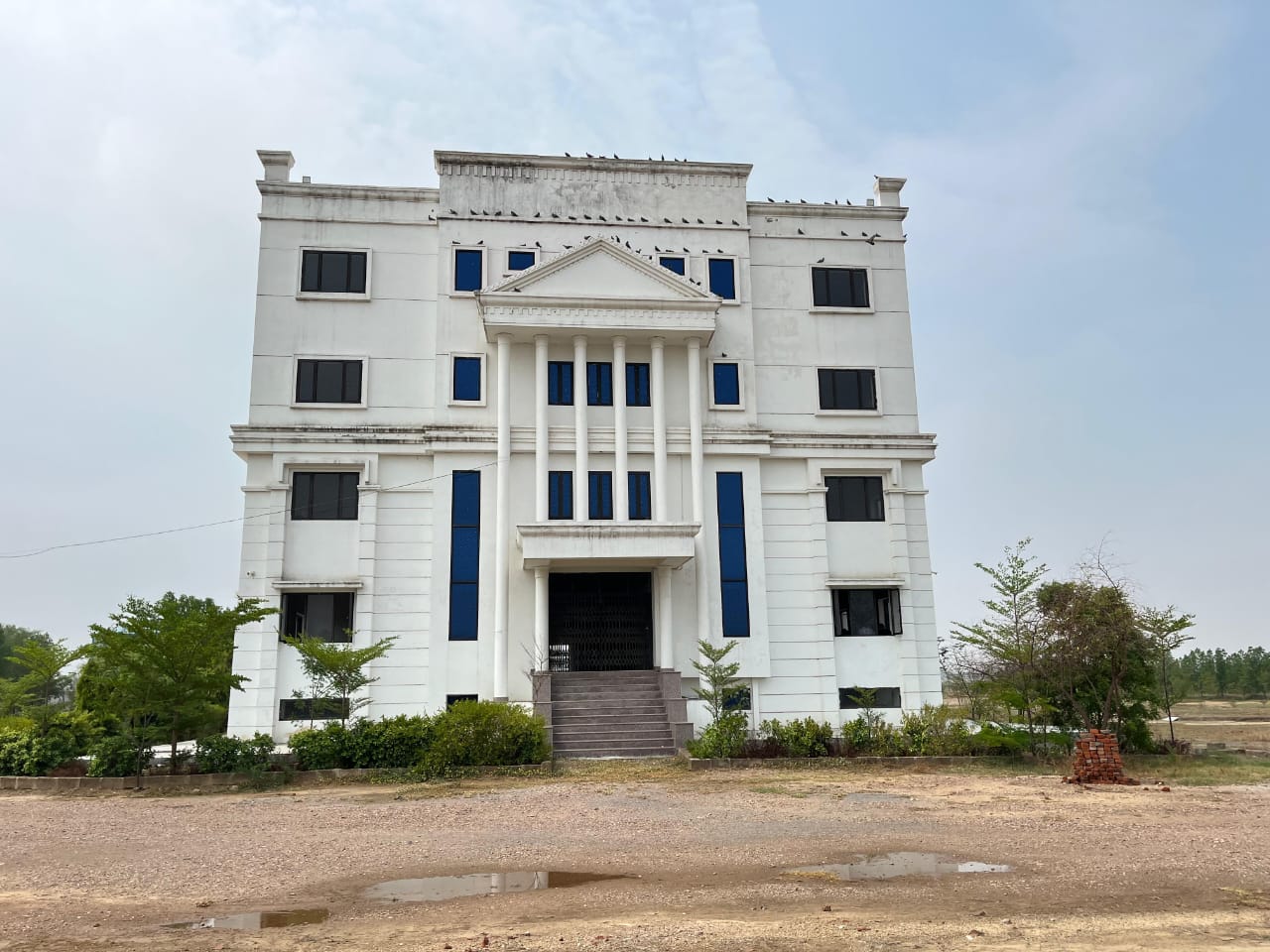 The front of the school building viewed head-on, showing tall blue-glazed windows either side of the pillared entrance