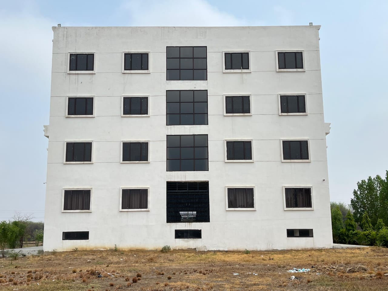 The rear elevation of the school building, a plain white facade with evenly spaced windows on four levels